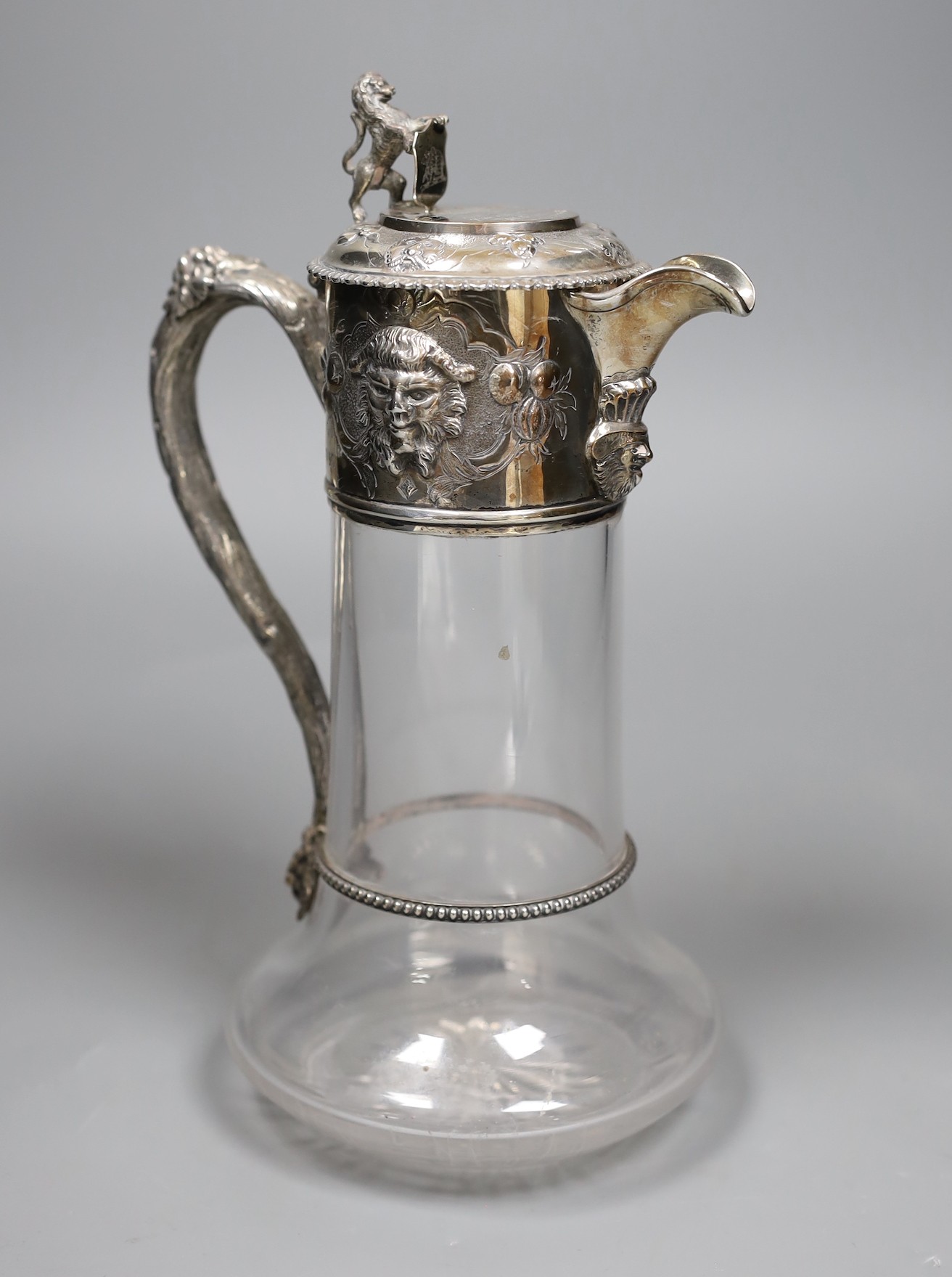 A Victorian silver mounted glass claret jug, by Richards & Brown, London, 1862, 26.9cm, decorated with masks and lion finial.